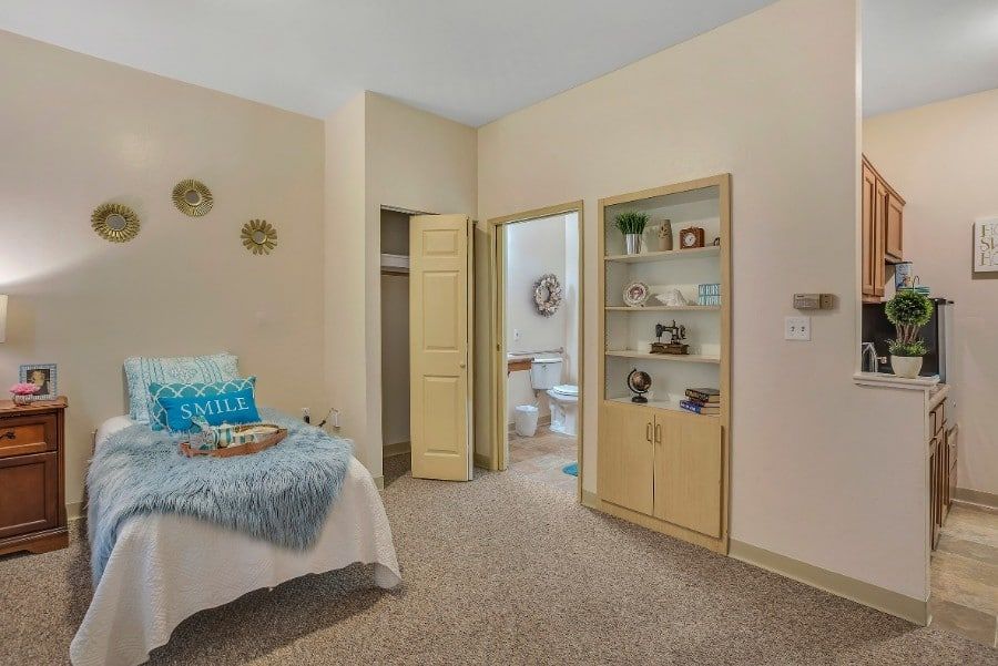A cozy bedroom with an open closet, adjoining bathroom, and decorative shelving.