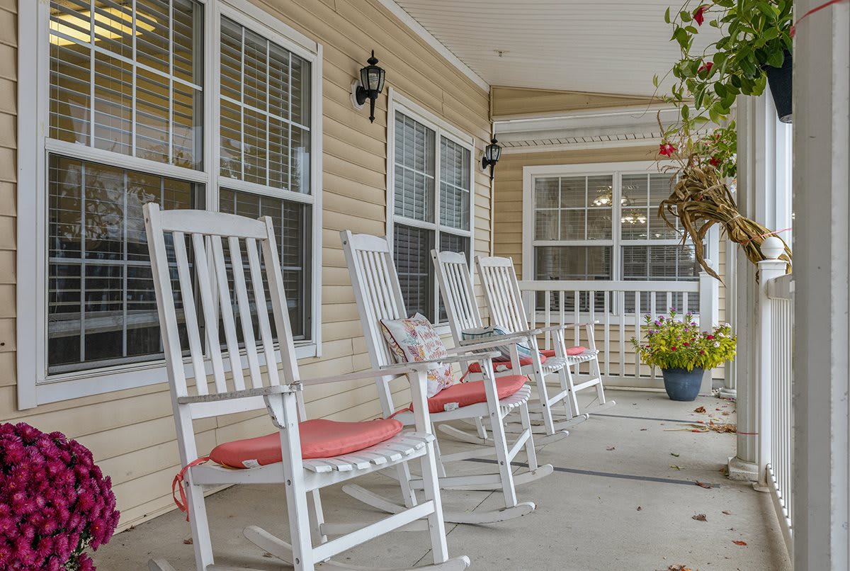 A cozy porch with white rocking chairs and decorative cushions.
