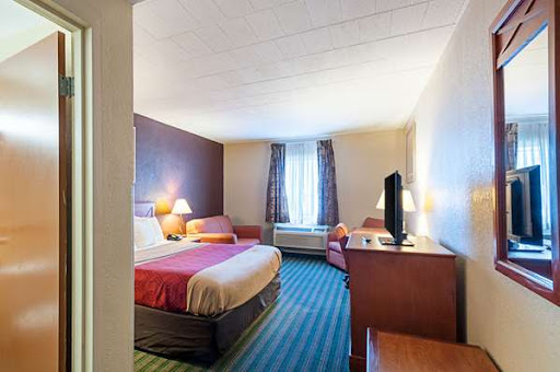 A cozy hotel room featuring a queen bed, seating area, and modern amenities.