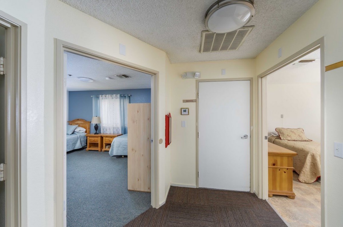 A hallway leading to a bedroom and bathroom, typical of a care facility setting.