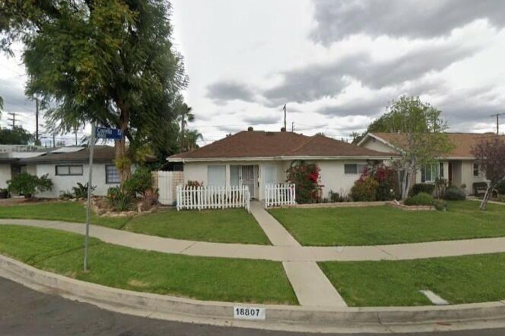 A suburban house with a well-maintained lawn and trees under a cloudy sky.