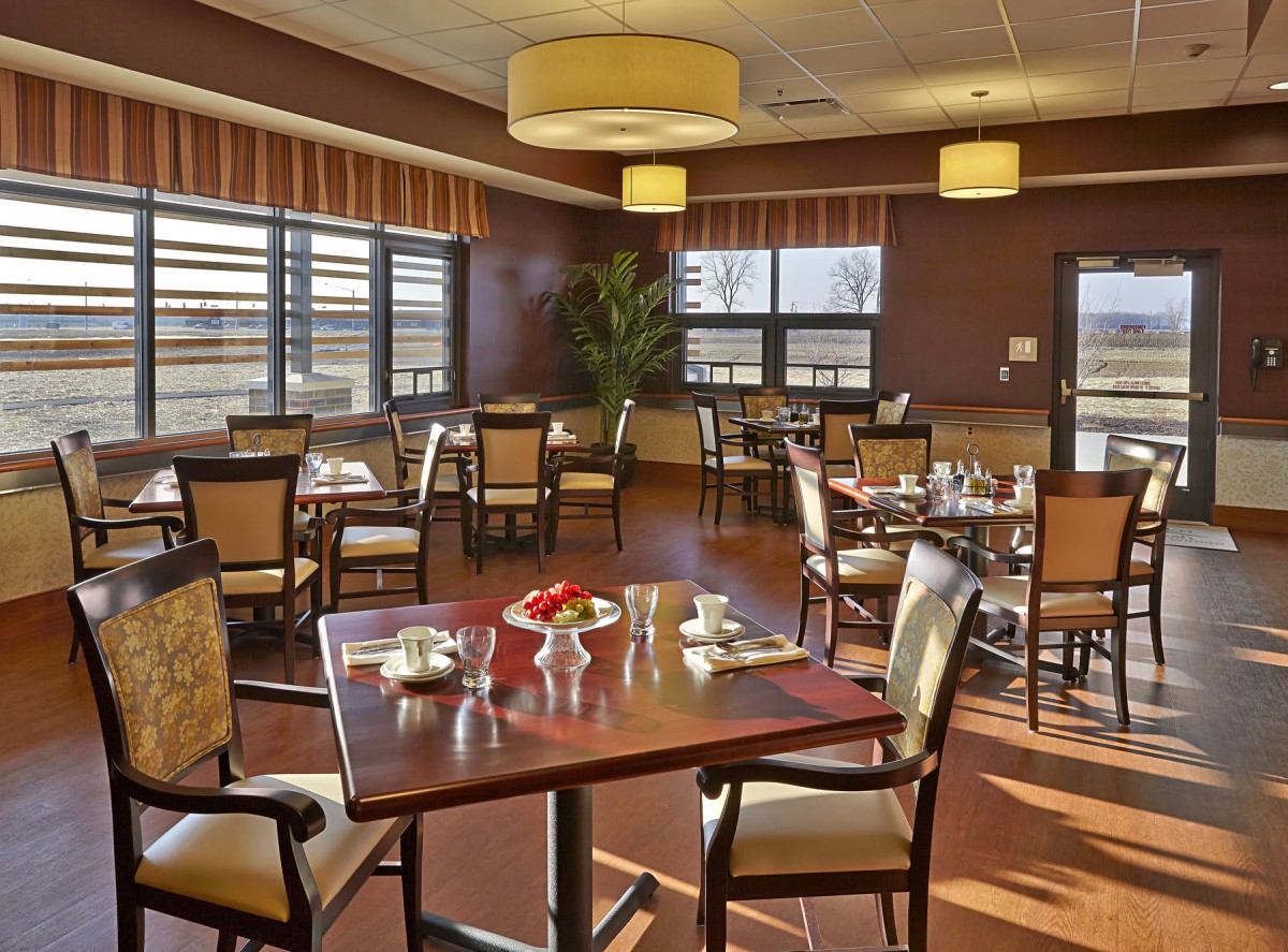A well-lit dining area with neatly arranged tables and chairs, featuring large windows and stylish interior decor.