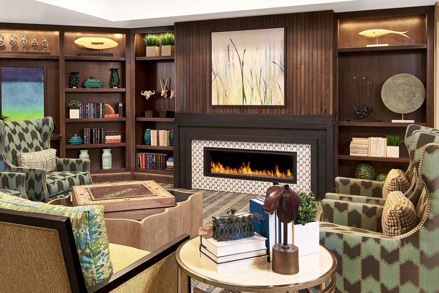 A cozy living room with a fireplace, surrounded by bookshelves and elegant decor.