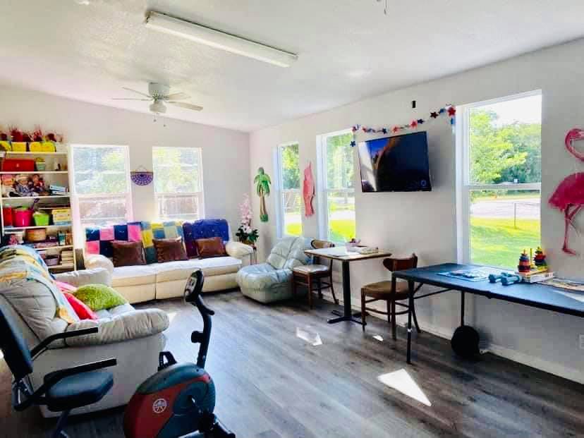 A bright and cozy living room with a sofa, exercise bike, and flat-screen TV.