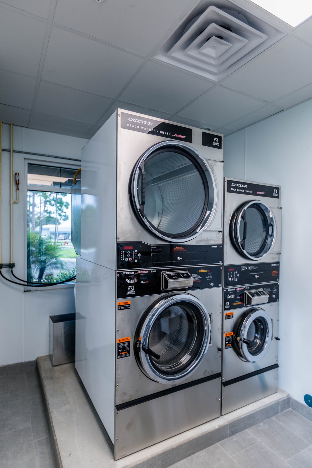 A pair of stacked industrial washing machines and dryers in a laundromat.