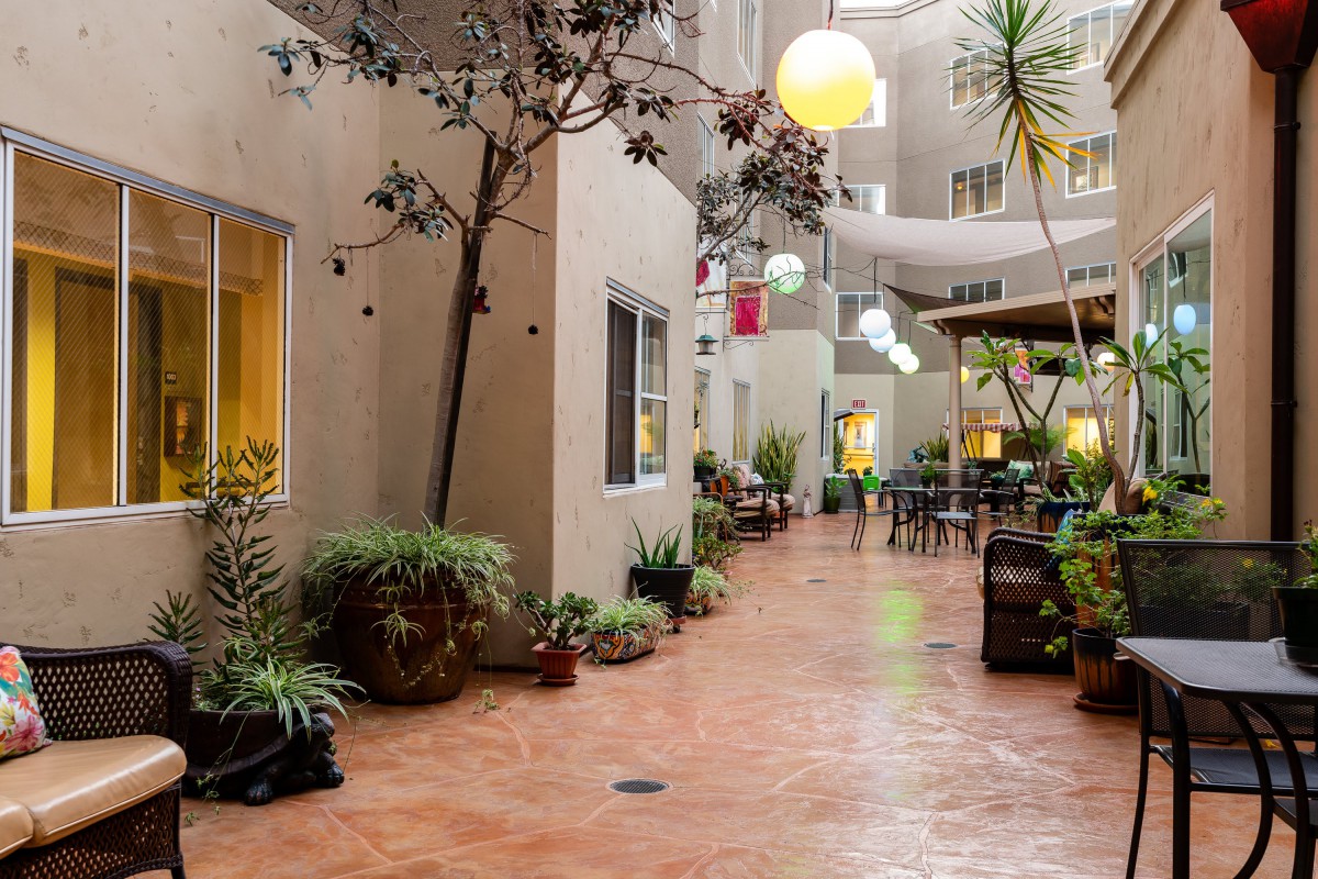 A cozy indoor courtyard with plants, seating, and decorative lights.