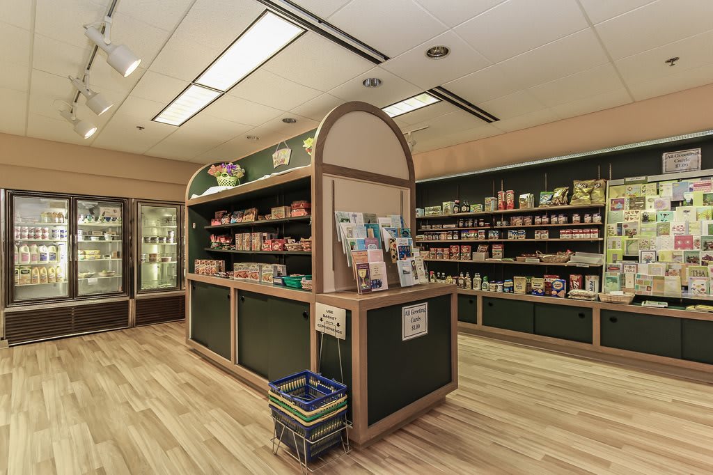 The image shows the interior of a small grocery store with shelves stocked with various products.