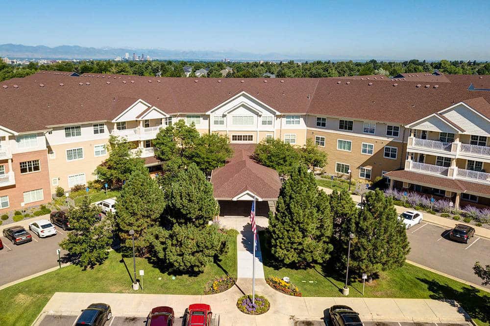 Aerial view of a residential building with surrounding trees and a parking lot.