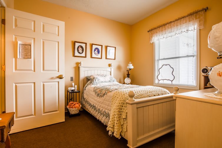 A cozy bedroom with a single bed, decorated with framed wall art and warm lighting.