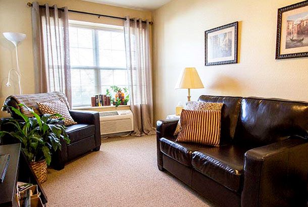 A cozy living room with leather seating, a lamp, and a window allowing natural light in.