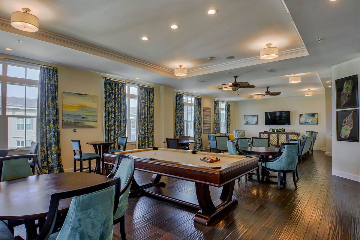 A modern recreation room featuring a billiards table, ample seating, and elegant decor.