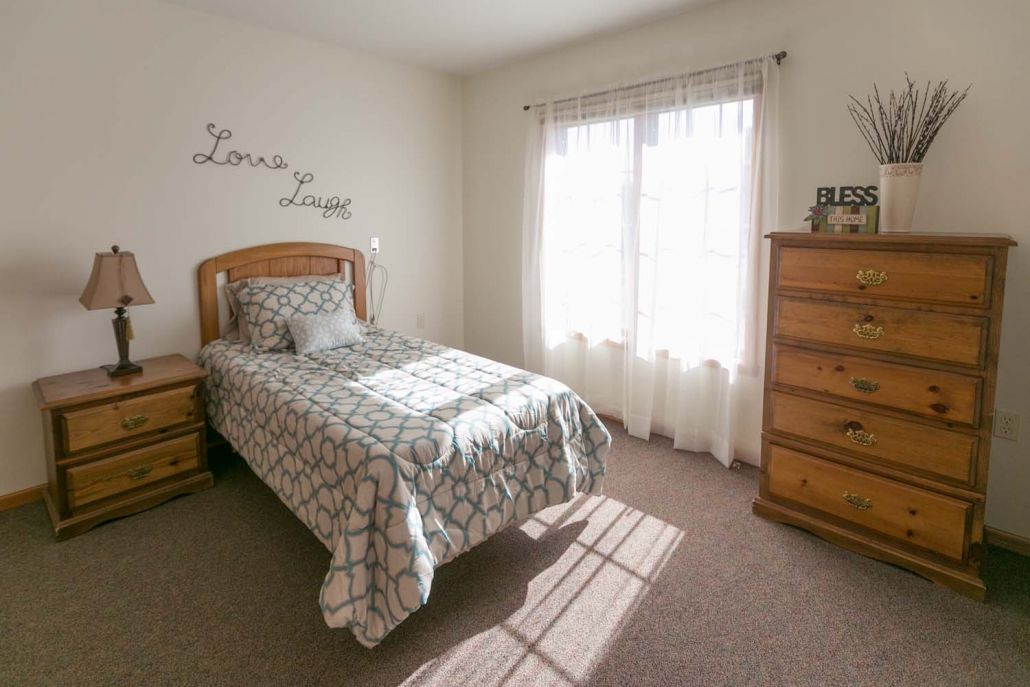A cozy bedroom with a single bed and sunlight streaming through the window.