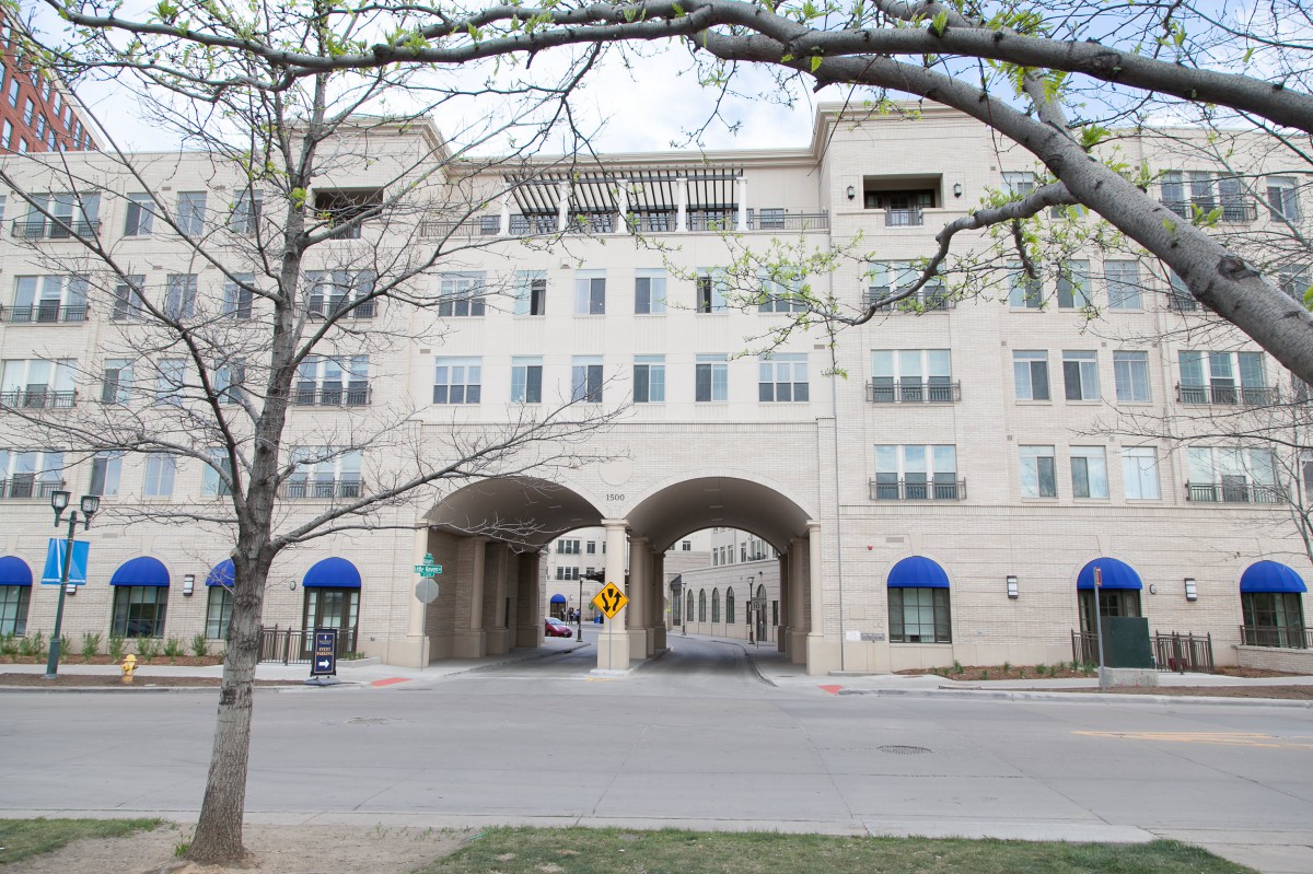 A modern multi-story building with arched entrances and blue awnings.