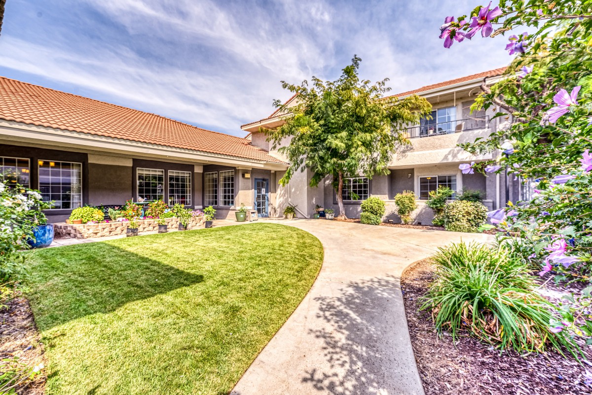 A beautiful two-story house with a well-maintained garden and paved walkway.