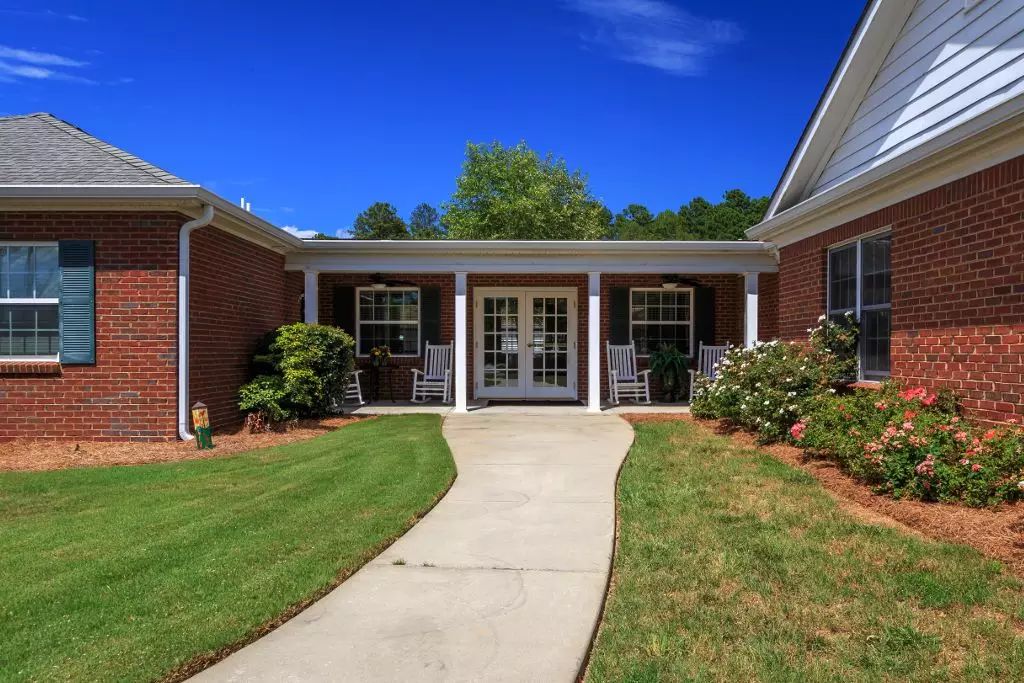 A welcoming entrance to a brick building with a neatly landscaped pathway.