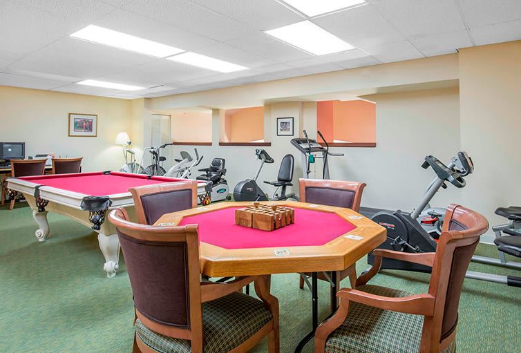 A multi-purpose room featuring a poker table and fitness equipment including exercise bikes and treadmills.