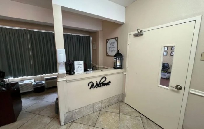 A hotel reception area with a welcome sign and tiled flooring.