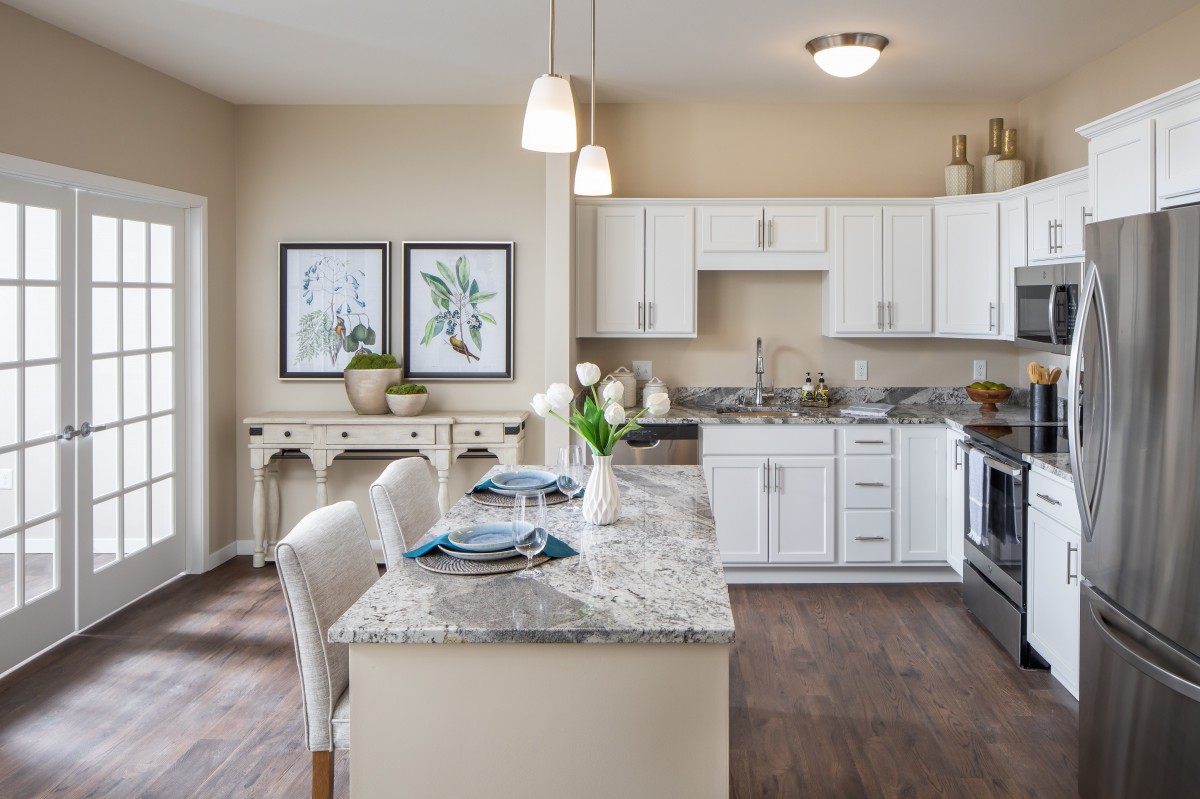 A modern kitchen with white cabinetry, a granite island, and elegant decor.