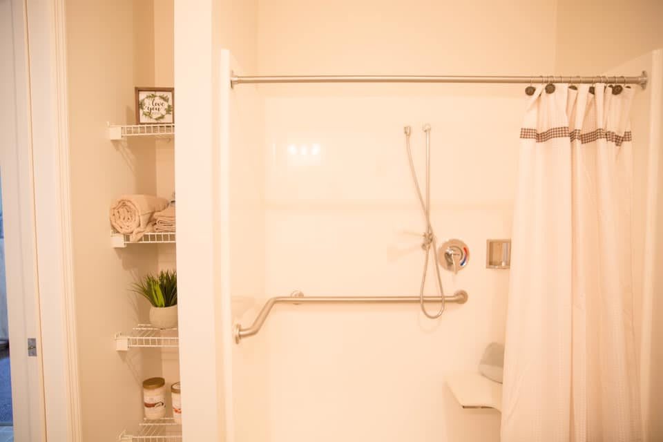 A well-organized bathroom featuring a walk-in shower with a grab bar and adjacent shelving.
