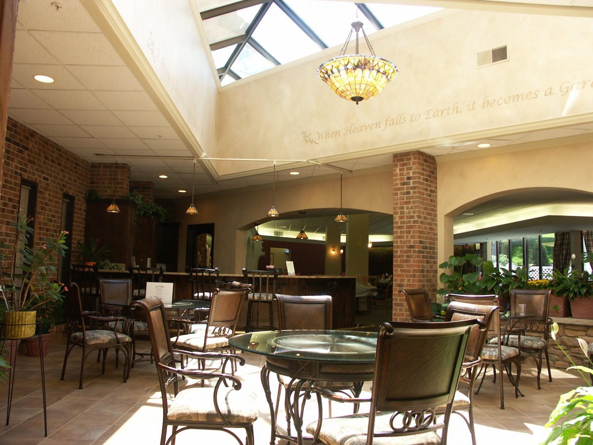 A well-lit restaurant interior with tables and chairs under a skylight.