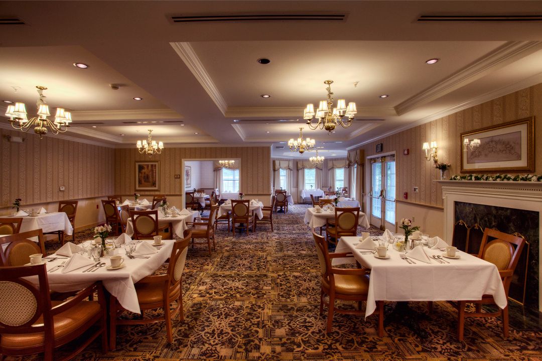 An elegant restaurant dining room with neatly arranged tables and classical chandeliers.