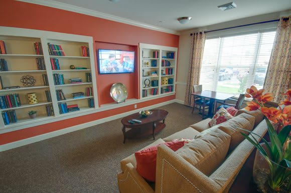 A cozy living room with a sofa, bookshelves, and a television.