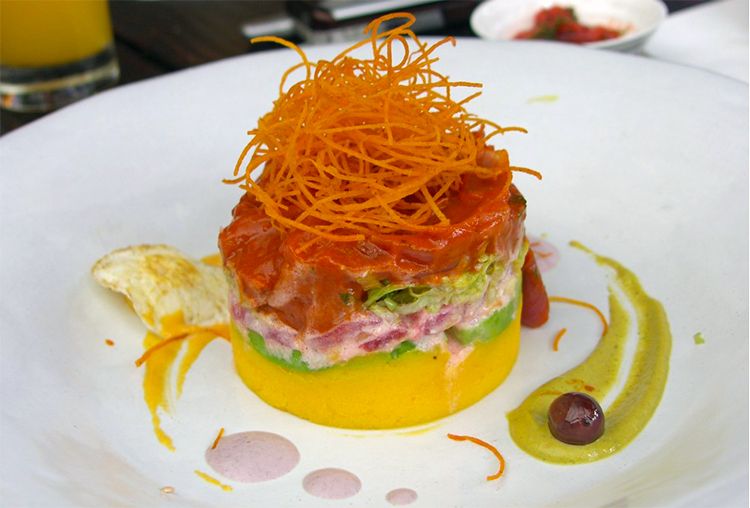 A beautifully plated gourmet dish featuring layered ingredients and artistic garnishes.
