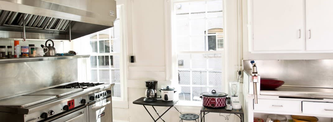 A bright kitchen space featuring a coffee maker and crockpot on a small table by the window.