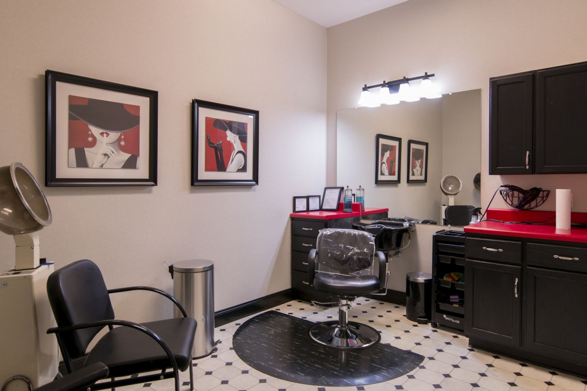 A modern hair salon with stylish decor, featuring a hairdressing station and artwork on the walls.