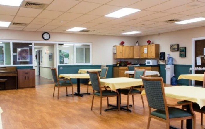 A communal dining area with tables, chairs, and a kitchenette.