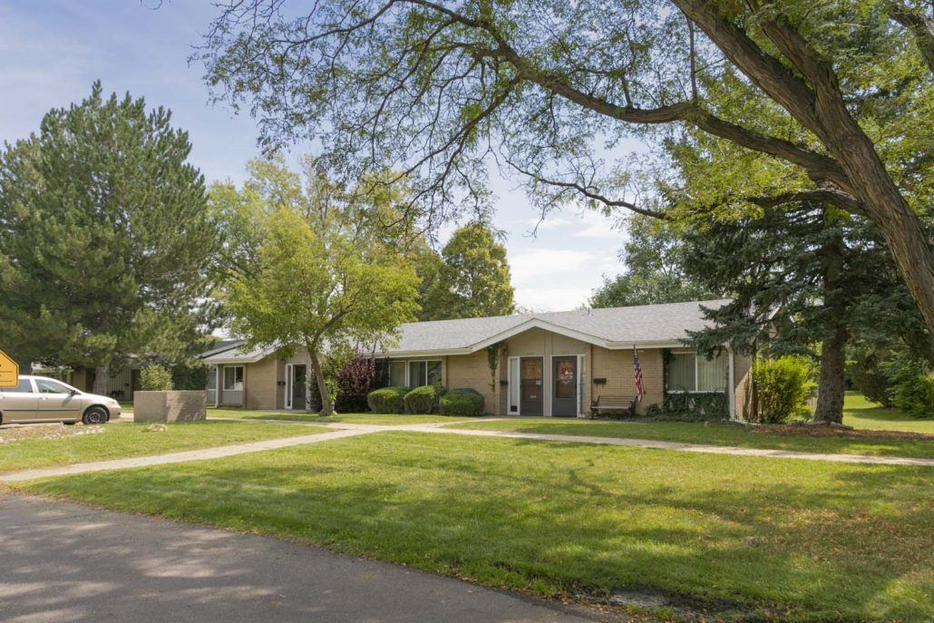 A suburban house surrounded by trees and a well-maintained lawn.