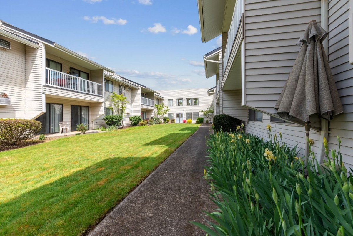 A well-maintained apartment complex with a green lawn and pathway.