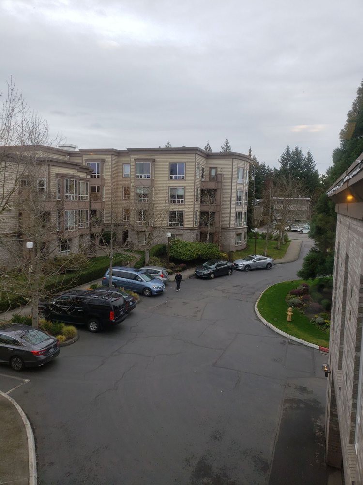A view of an apartment complex with parked cars under an overcast sky.