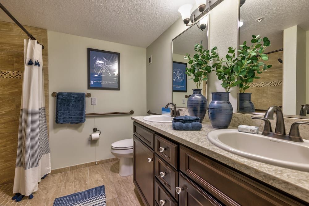 A well-designed bathroom with a large mirror, wooden cabinets, and blue-themed decor.