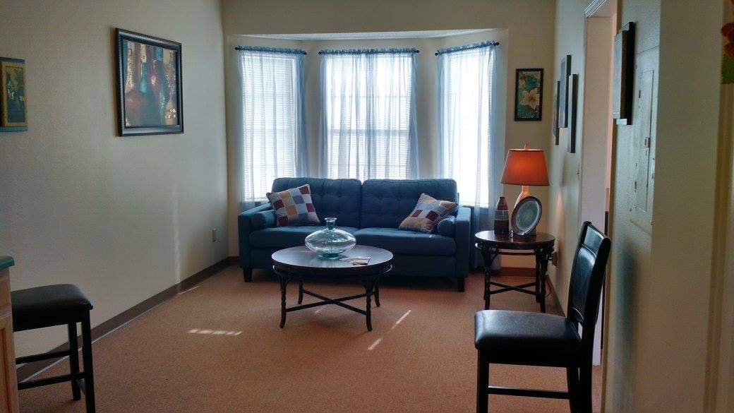 A cozy living room with a sofa, coffee table, and bright windows.