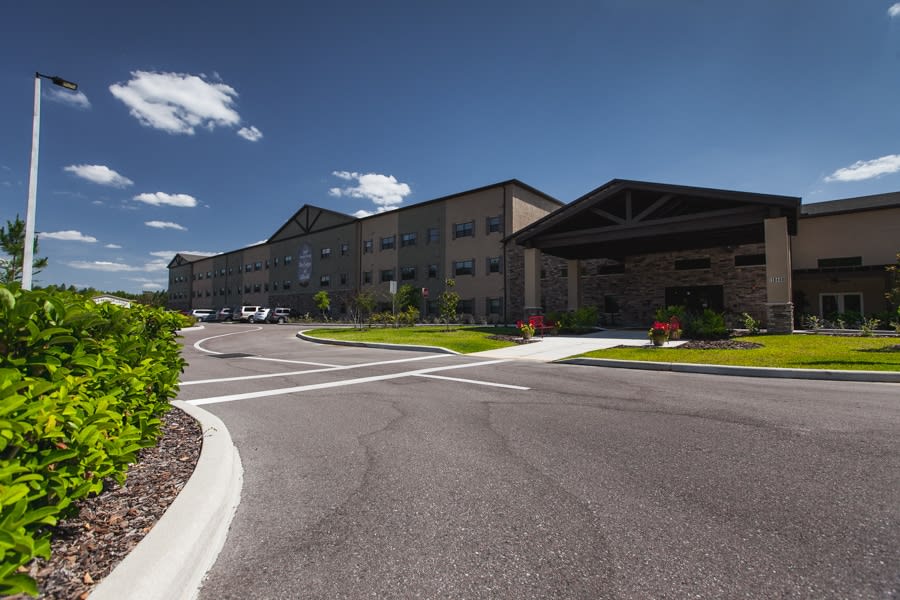 A modern building complex with a spacious parking lot on a sunny day.