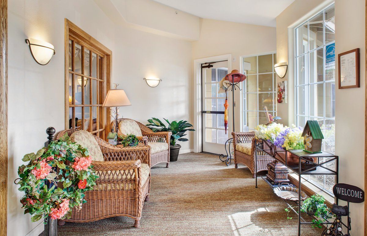 A cozy lobby with wicker furniture, decorative plants, and ample natural light.