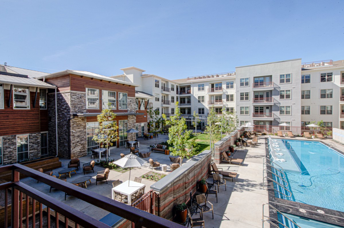 A modern apartment complex featuring a spacious courtyard with a pool and outdoor seating areas.