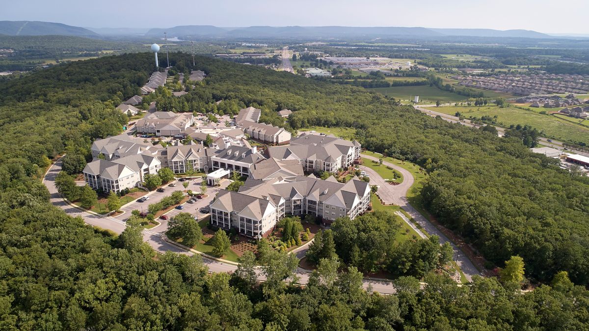 Aerial view of a resort complex surrounded by lush greenery and rolling hills.
