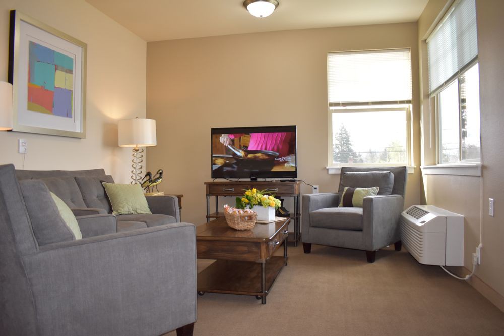 A cozy living room with modern furniture, featuring a sofa, armchair, and television.