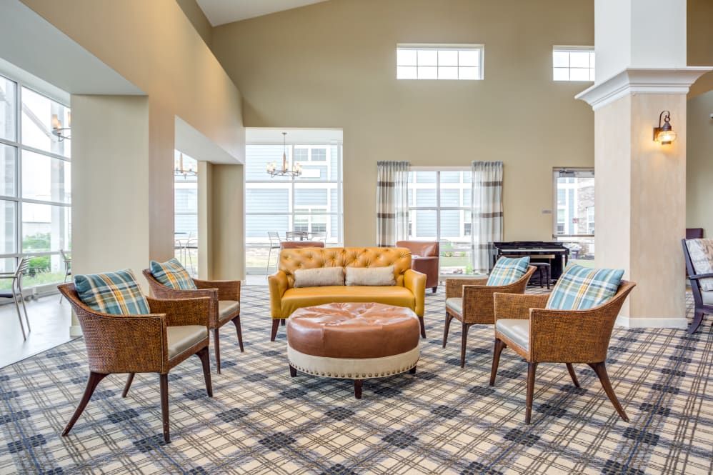 A modern living room with a yellow sofa, plaid carpet, and large windows.