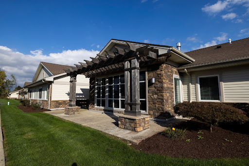 A beautifully designed modern home with a stone facade and a pergola, surrounded by lush landscaping.