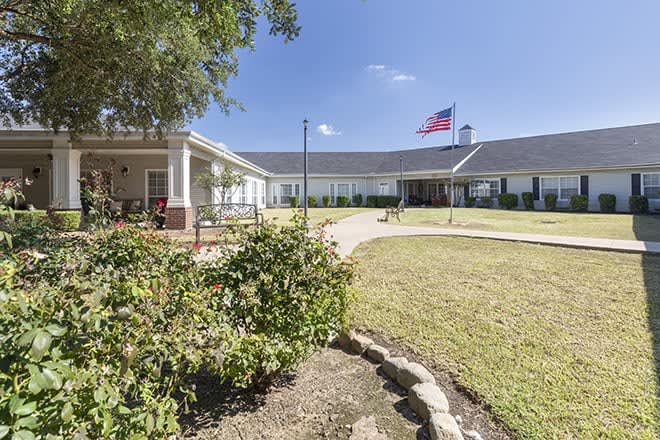 A large house with a garden and an American flag flying in the front yard.