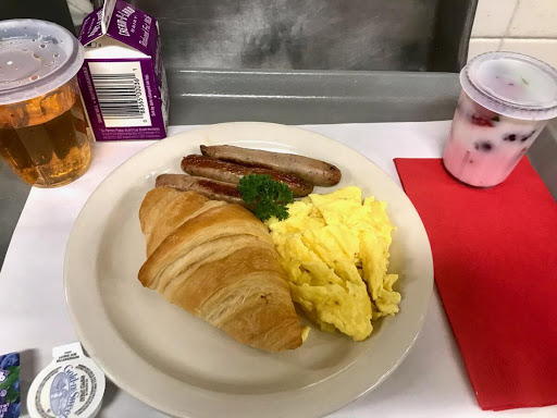 A delicious breakfast plate featuring scrambled eggs, a croissant, and sausage.
