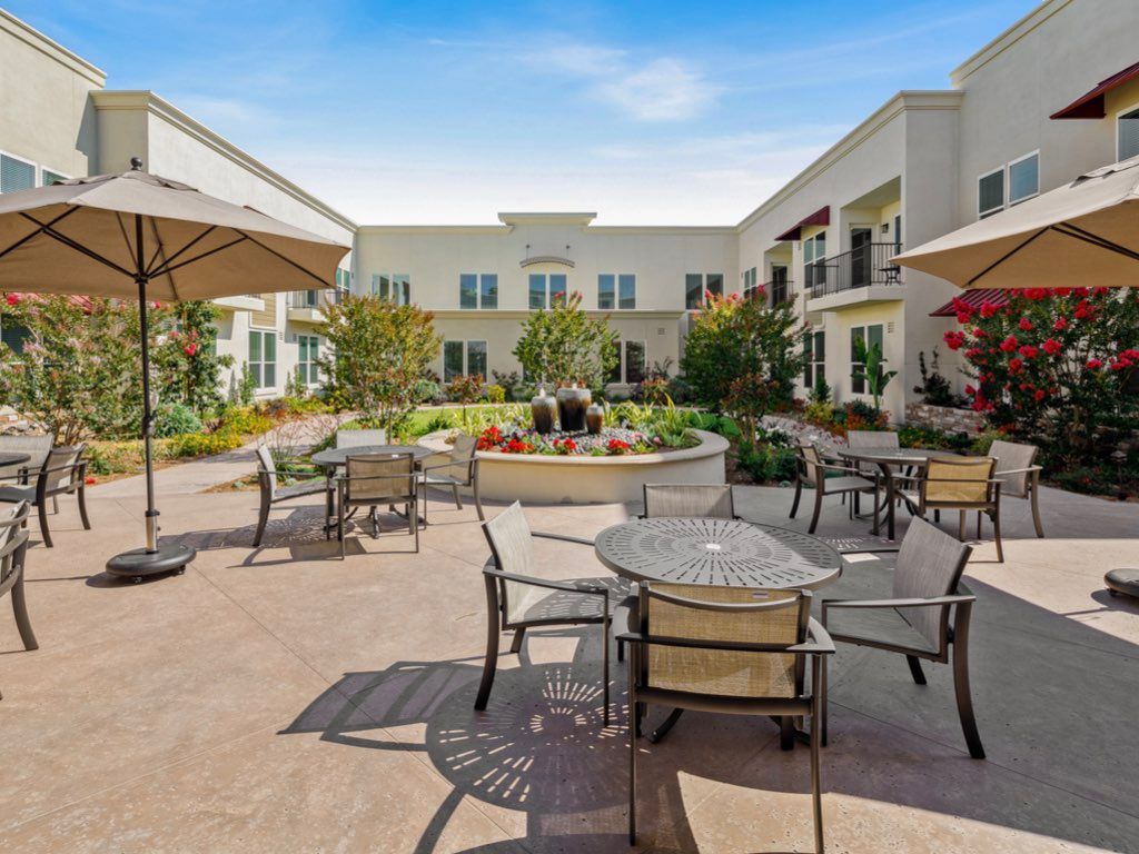 A spacious courtyard with outdoor seating and umbrellas surrounded by a modern building.