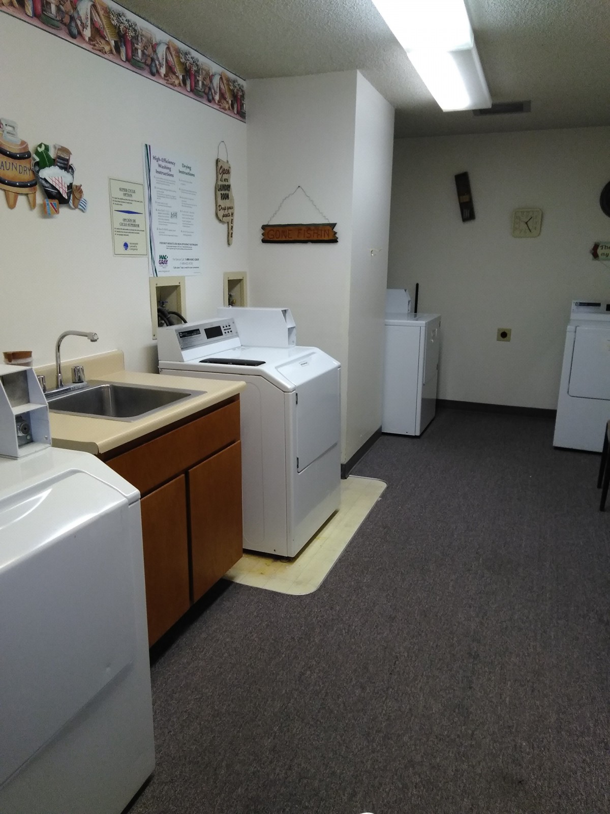 A tidy laundry room featuring multiple washing machines and a sink.