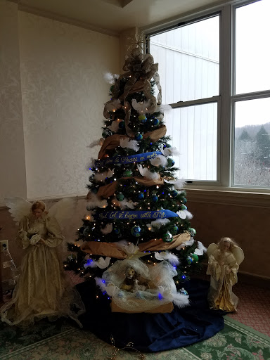 A beautifully decorated Christmas tree with ornaments, surrounded by angel figurines and a nativity scene.