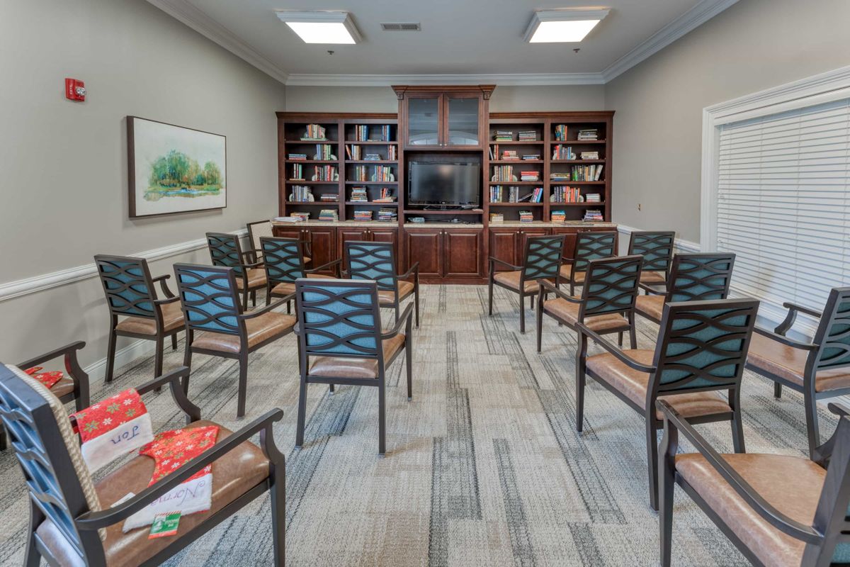 A well-organized meeting room with chairs arranged in rows facing bookshelves and a television.