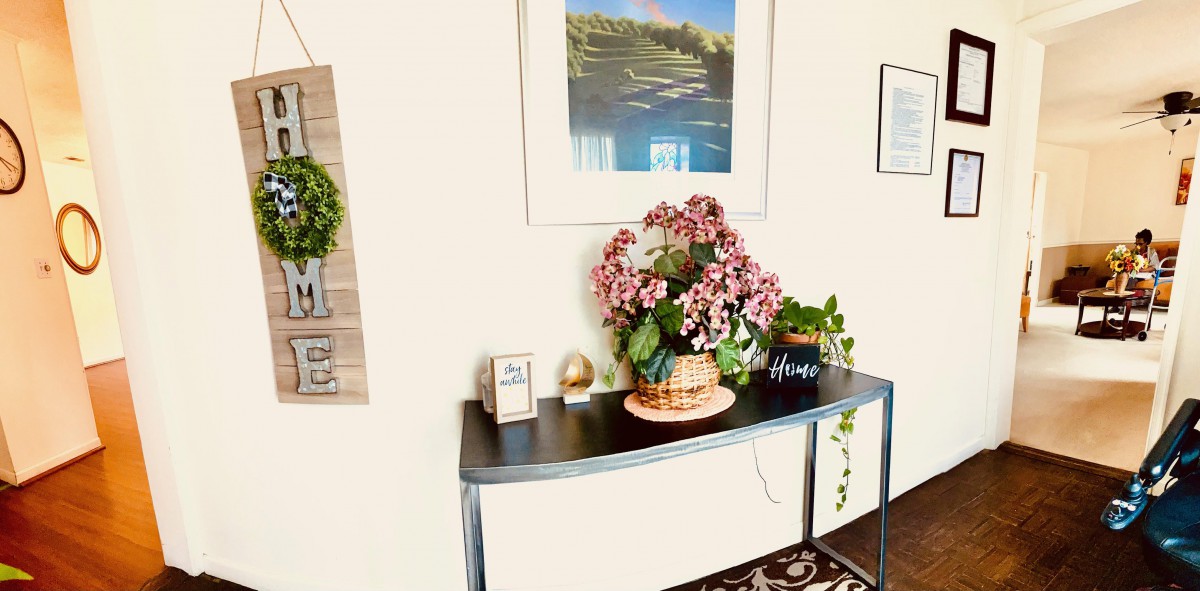 A stylish console table adorned with a vibrant bouquet of flowers and decorative items beneath a framed landscape painting.