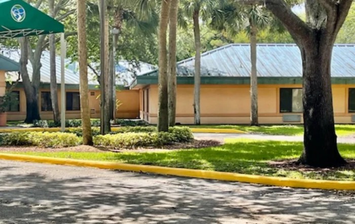 A view of buildings surrounded by trees and well-maintained landscaping.